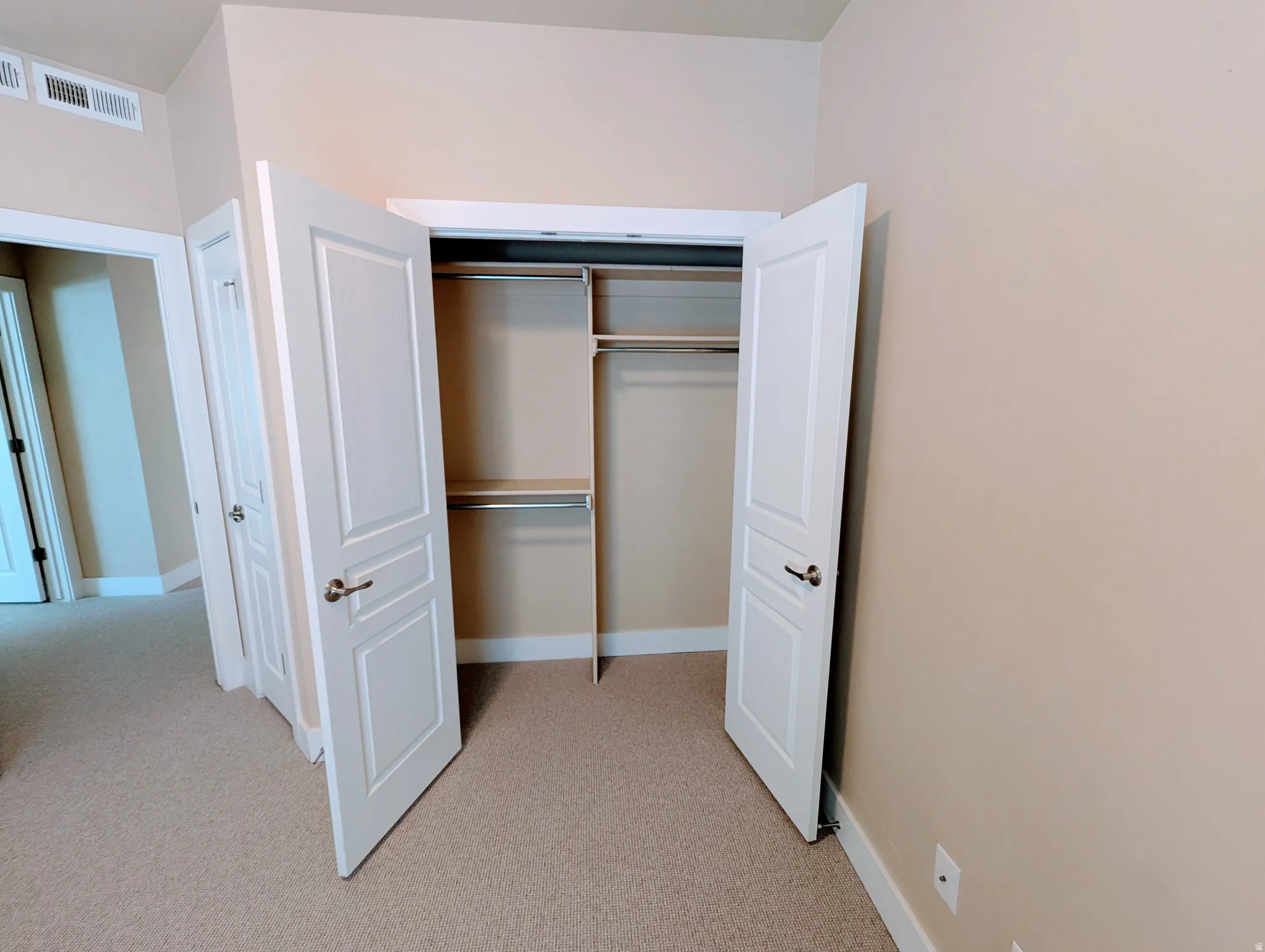 Closet space featuring bi-fold panel doors and integrated shelving with metal rods