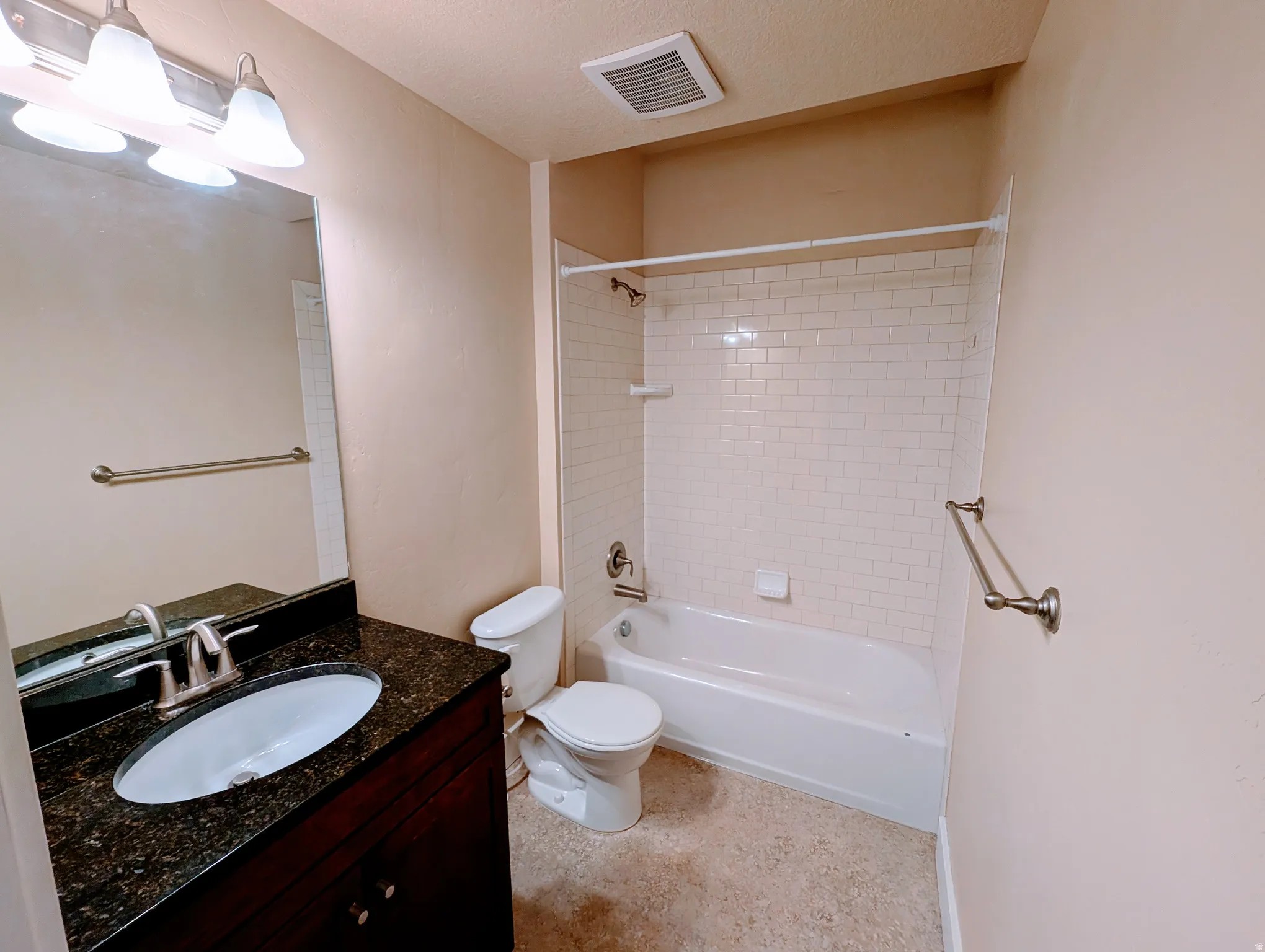 Bathroom featuring a dark wood-finish vanity with a dark speckled countertop, an undermount sink, and a brushed nickel faucet