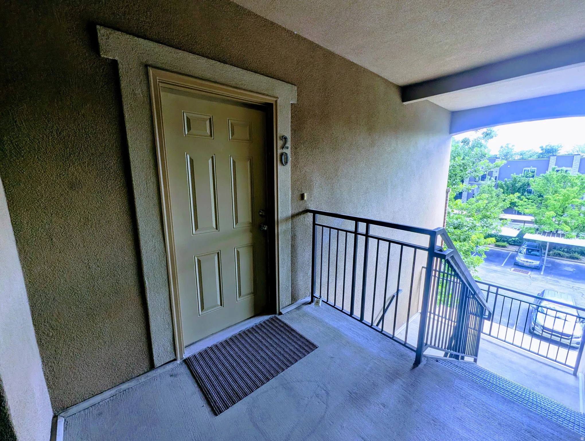 Entry door with panel detailing and visible unit numbering, set within textured stucco exterior walls