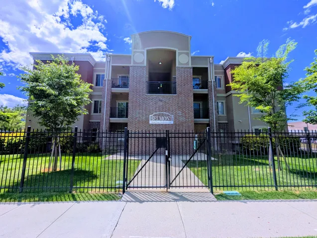 Multi-story building featuring a brick and stucco exterior, multiple private balconies, and a central arched entrance