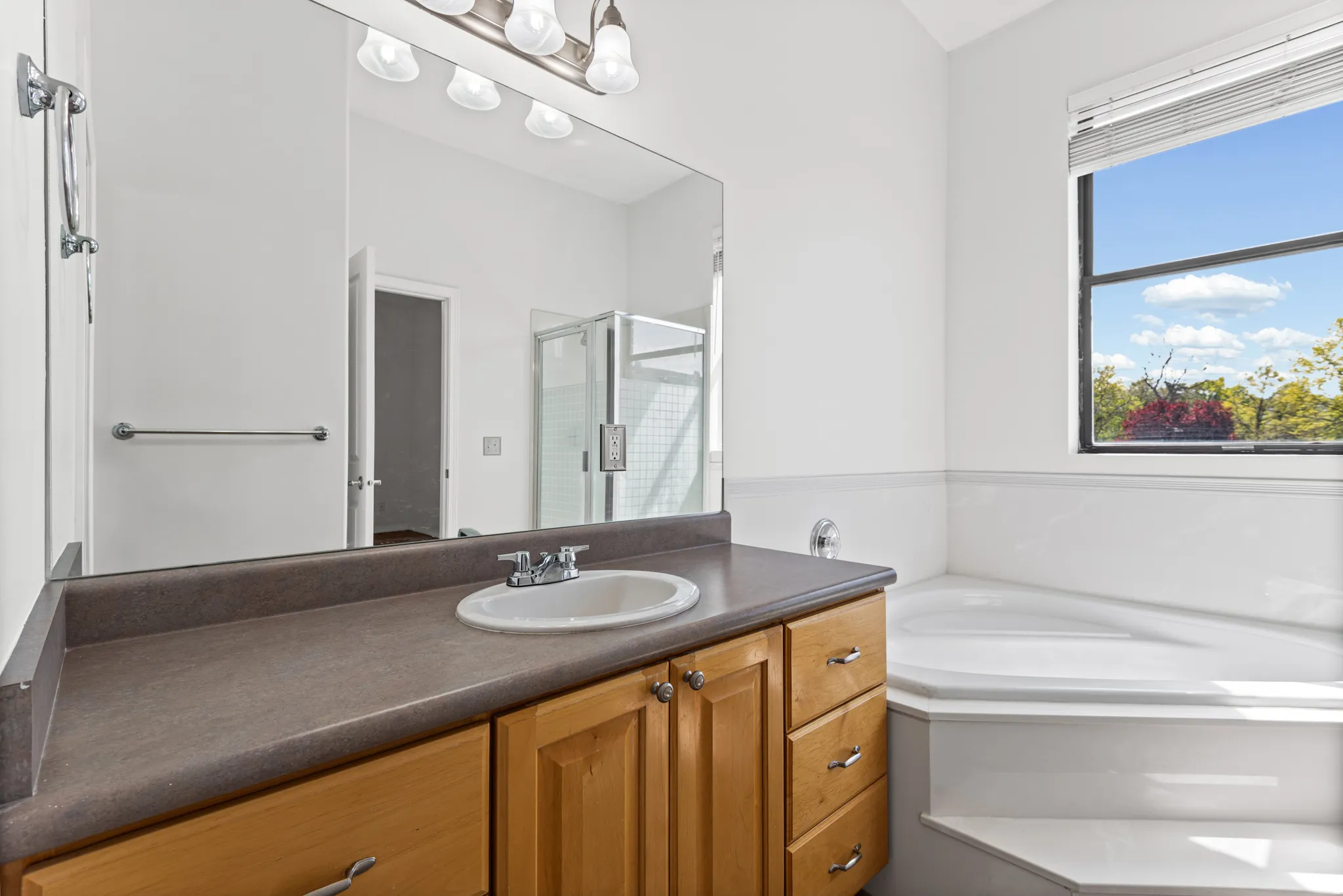 Big and bright bathroom with a soaking tub and there is a large walk in shower to the left.