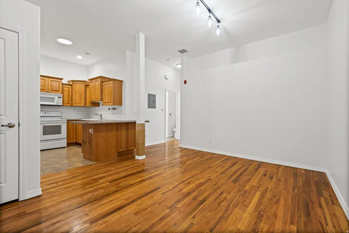 Open-concept living area featuring wood-finish flooring, white walls, and track lighting