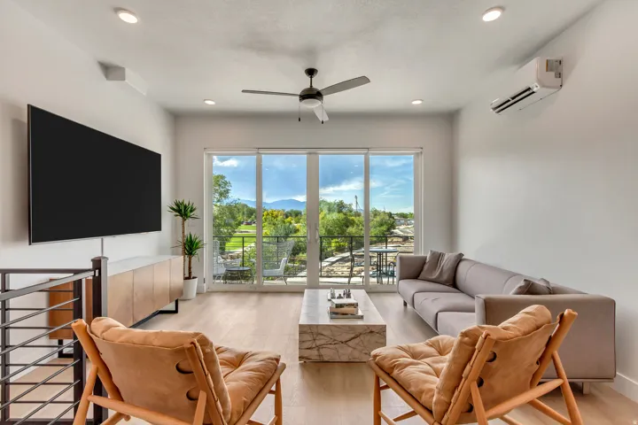 Spacious living area featuring expansive glass sliding doors, wood-finish flooring, recessed lighting, and a ceiling fan