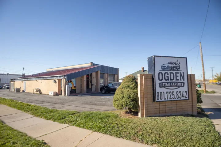 Commercial building featuring a prominent brick sign, ample asphalt parking, and an angled blue metal roof