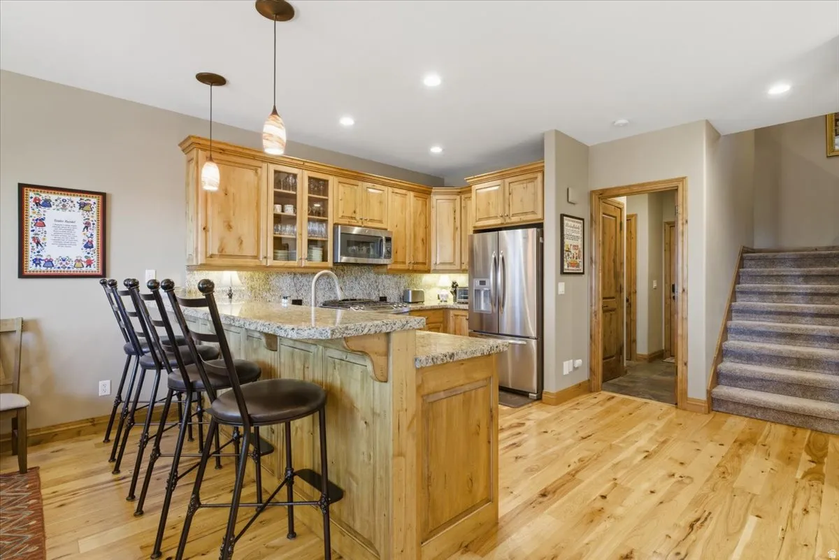 Kitchen featuring wood-finish cabinetry, stainless steel appliances, and a peninsula with a stone countertop