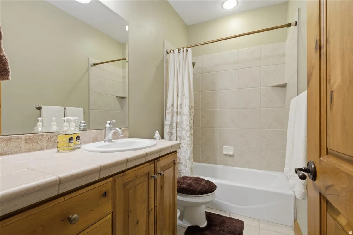 Bathroom featuring a tiled vanity with integrated sink, wood cabinetry, and a full-width mirror