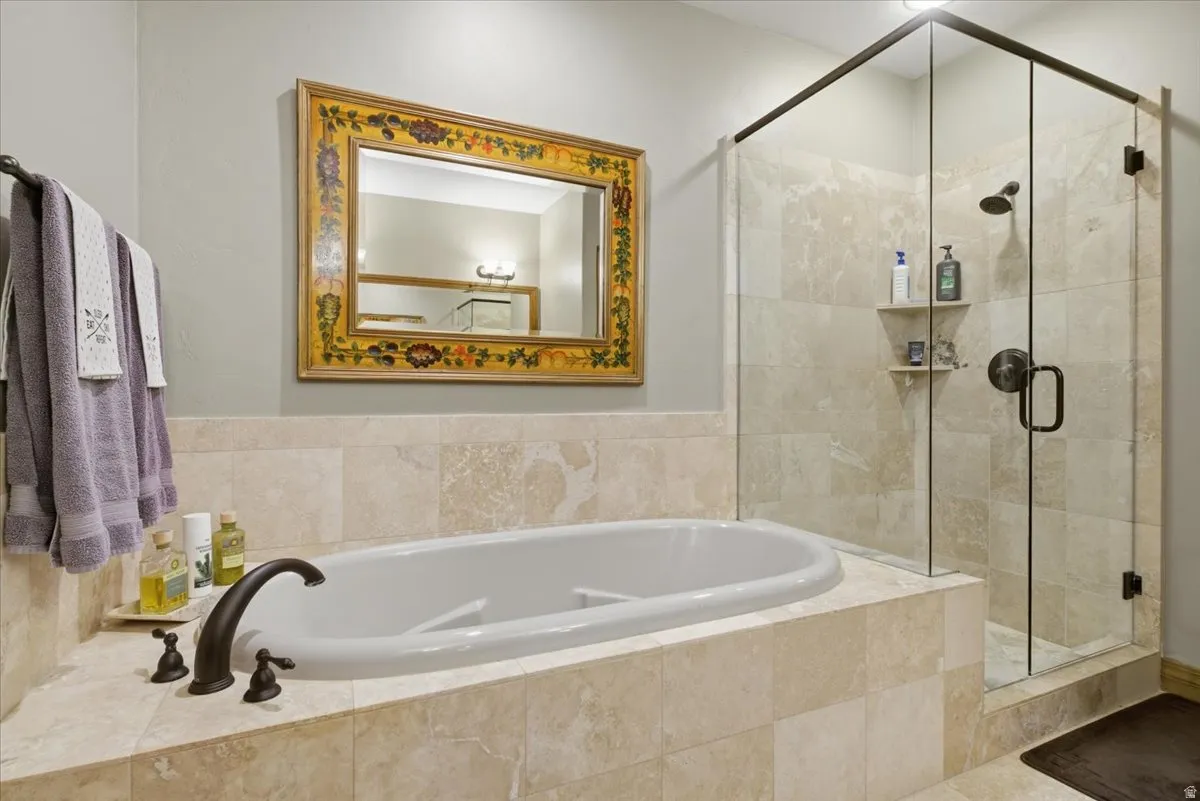 Master bathroom featuring a bronze-finish faucet, a glass-enclosed shower with tile surround, and a decorative mirror