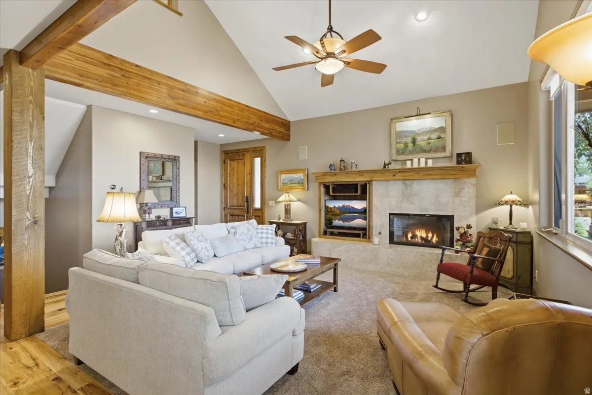 Spacious living area featuring a vaulted ceiling with exposed wood beams, a ceiling fan, and recessed lighting