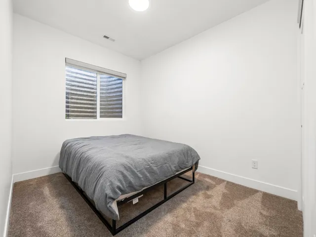 Compact room featuring neutral carpeting, white walls, and a window with blinds