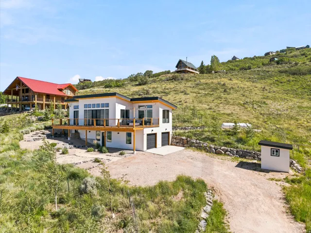 Modern exterior with a flat roofline, expansive upper-level deck, multiple large windows, and an attached two-car garage