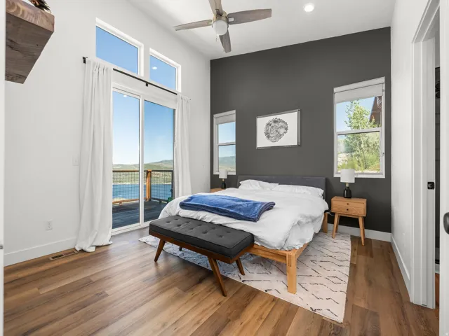 Spacious room featuring vaulted ceilings, wood-finish flooring, a contemporary ceiling fan, and direct access to an outdoor deck through a large glass slider