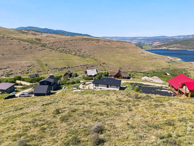 Expansive hillside property featuring a modern residence with a dark roof, surrounded by natural landscaping