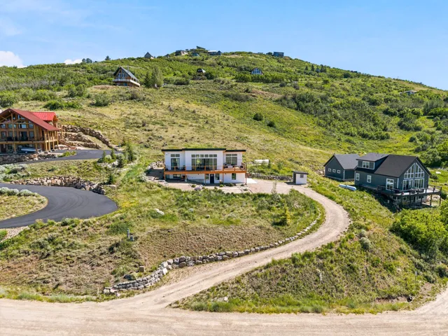 Modern home with multi-level decks and an expansive glass facade, set into a verdant hillside