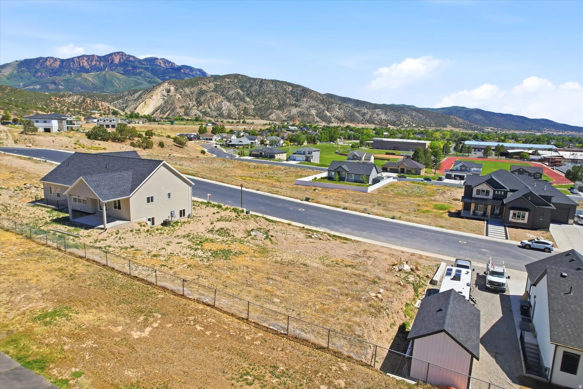 New construction with light-toned siding and a dark shingle roof, positioned on a sloped lot