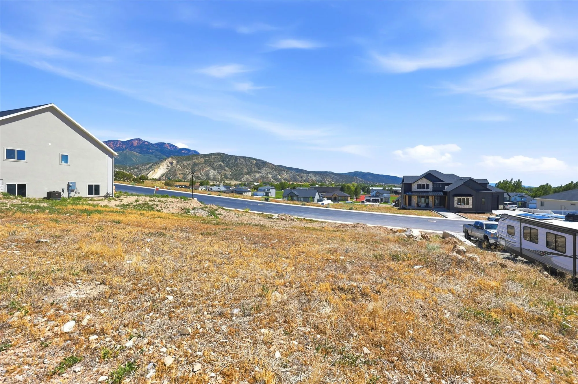 Expansive undeveloped lot featuring clear land, mountain backdrop, and paved street