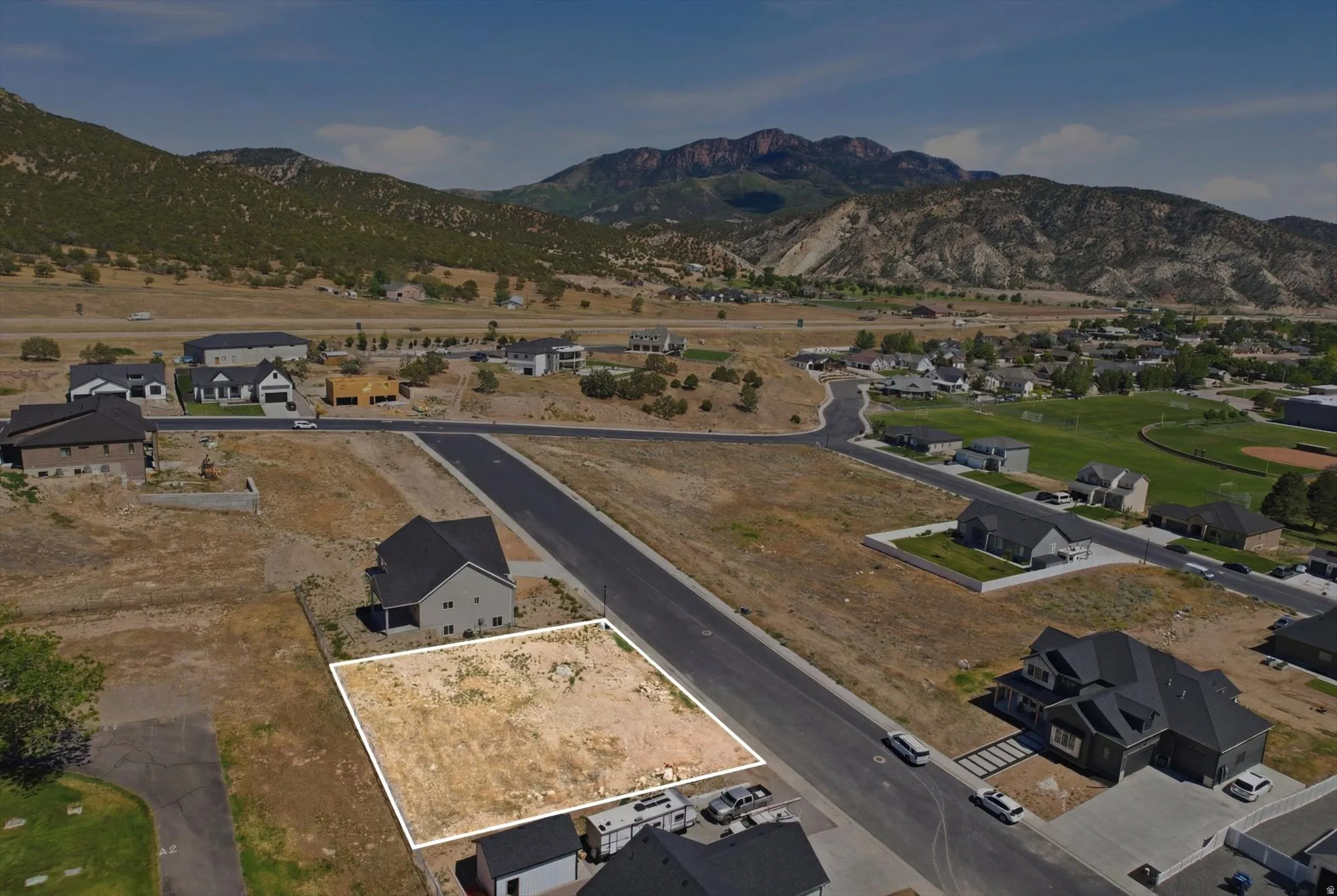 Cleared lot in a developing neighborhood, featuring paved roads and mountain scenery
