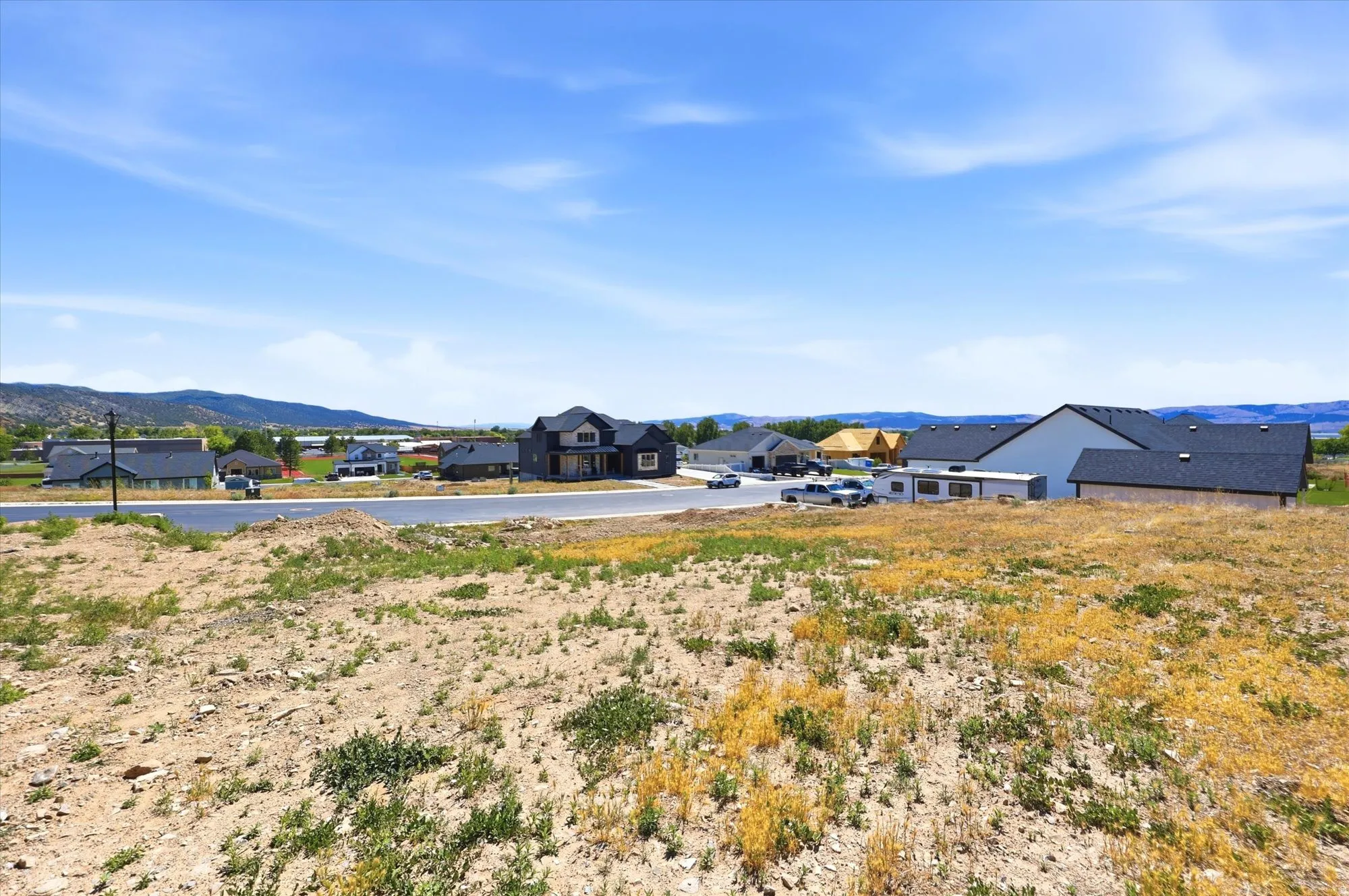 Expansive undeveloped lot featuring a paved road frontage, surrounded by existing residential structures