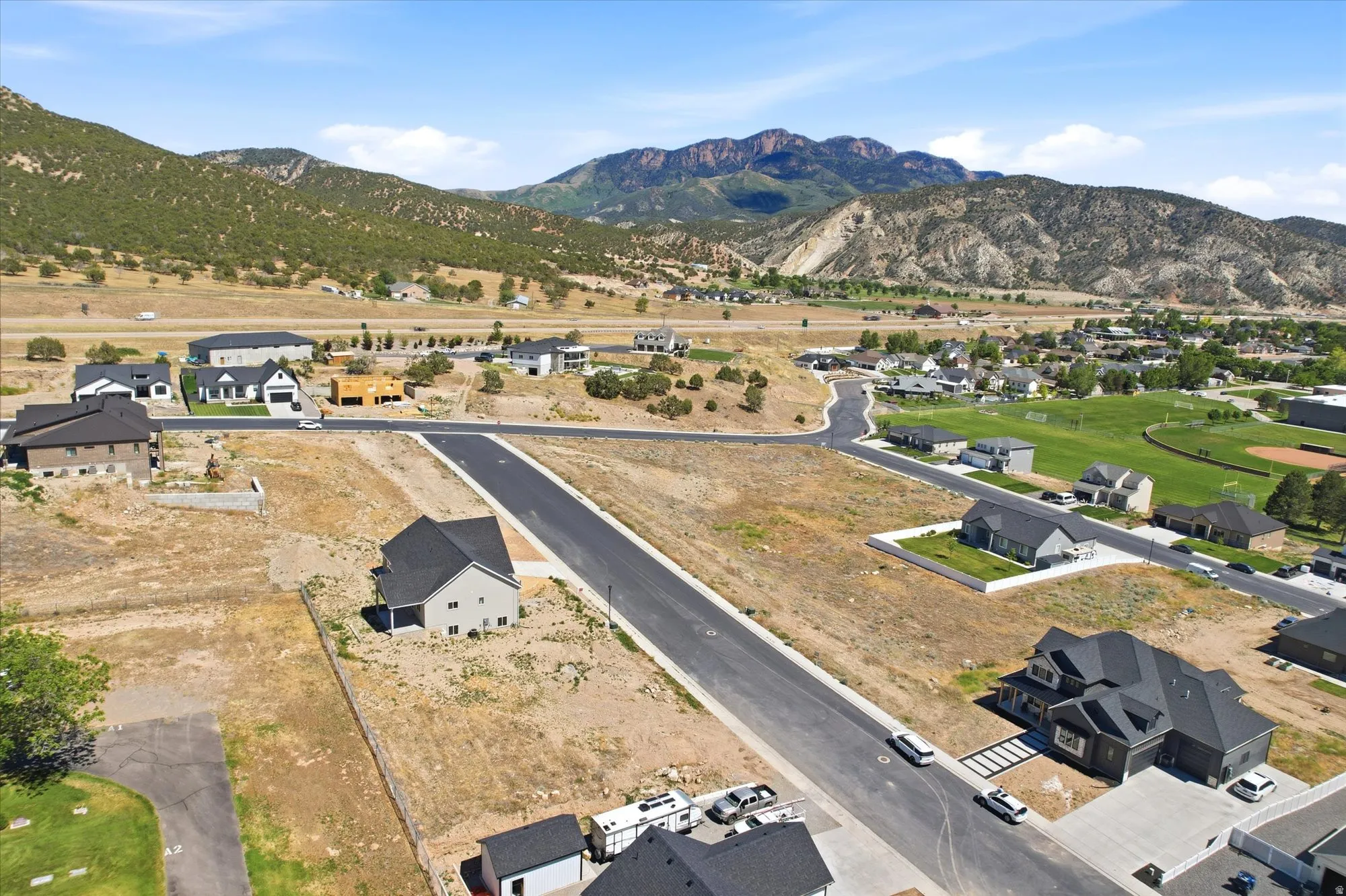 Spacious residential development featuring new construction and vacant lots, with paved roads and distant mountain scenery