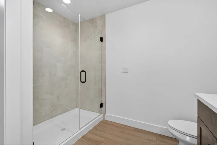 Walk-in shower featuring a frameless glass enclosure, tiled interior, and black hardware