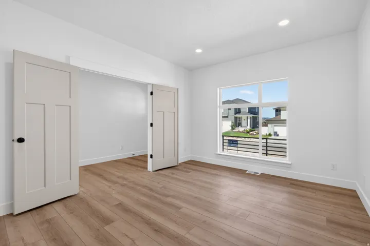 Spacious room with light wood-finish flooring, recessed lighting, and a large multi-pane window