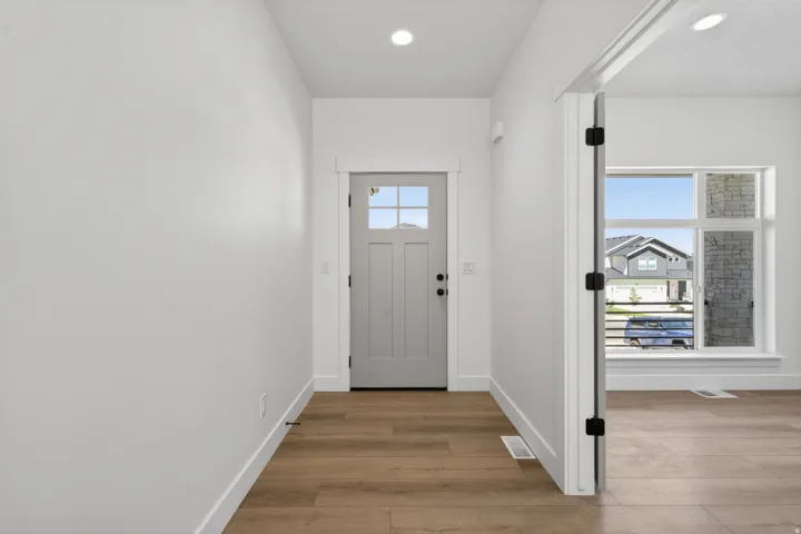 Entryway featuring a grey paneled door with glass inserts, wood-finish flooring, white baseboards, and recessed lighting