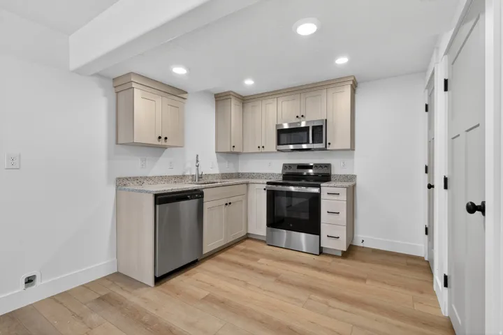Modern kitchen featuring wood-finish cabinetry, speckled countertops, and stainless steel appliances including a microwave, range, and dishwasher