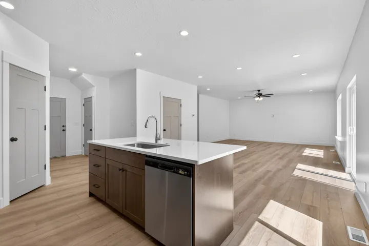 Kitchen island featuring a stainless steel sink, contemporary faucet, and integrated dishwasher