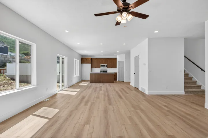 Open-concept living space featuring wood-finish flooring, recessed lighting, and a ceiling fan