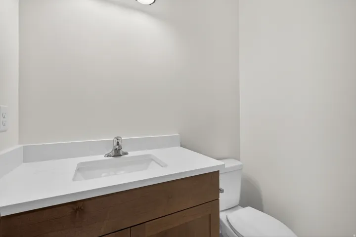 Bathroom featuring a wood-finish vanity with an integrated sink, white countertop, and brushed nickel faucet
