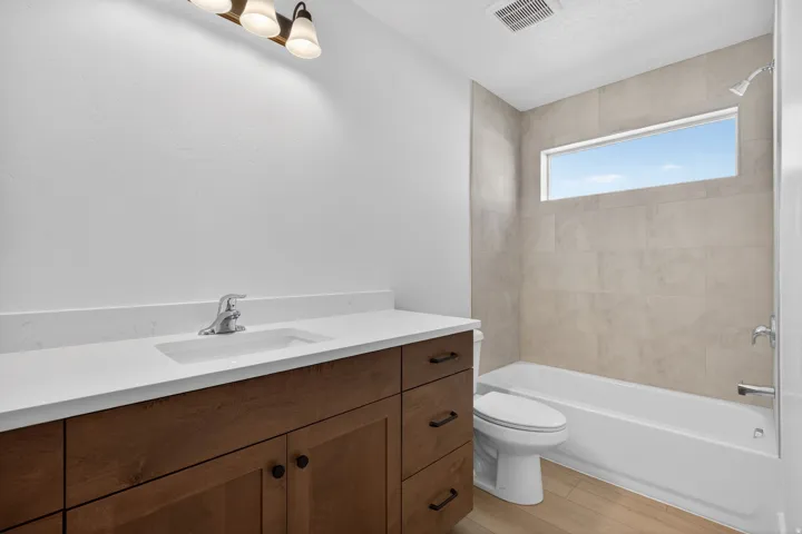 Bathroom featuring a single vanity with wood-finish cabinetry, a white countertop, and an integrated sink with a chrome faucet
