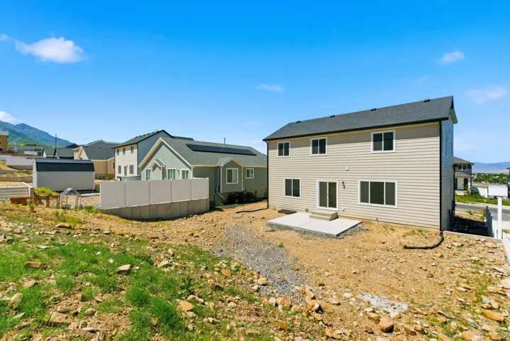 Rear exterior featuring neutral siding, a dark roof, and multiple windows