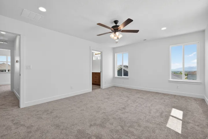 Spacious room featuring neutral carpeting, a ceiling fan with integrated lighting, recessed lighting, and white baseboards