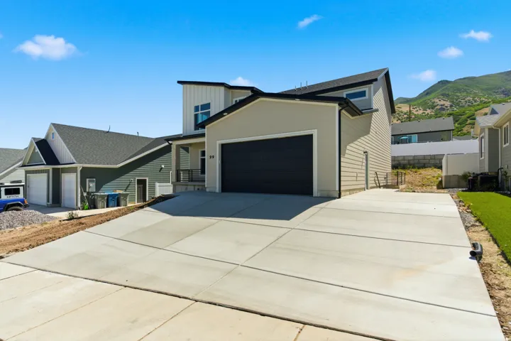Contemporary exterior featuring vertical and horizontal siding, a prominent dark garage door, and a spacious concrete driveway