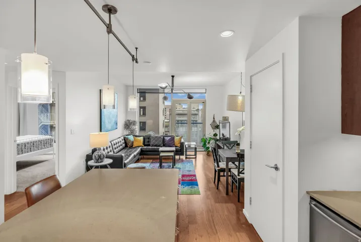 Open-concept living space featuring wood-finish flooring, recessed lighting, and a private balcony