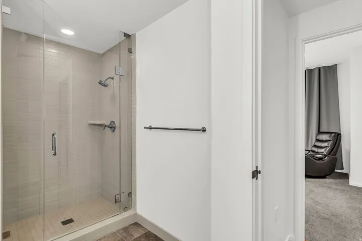 Contemporary shower enclosure featuring clear glass panels, a chrome showerhead, and light-toned tile walls