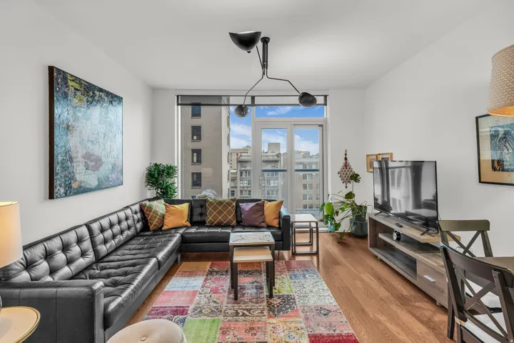Spacious living area featuring wood-finish flooring and ample natural light from floor-to-ceiling windows