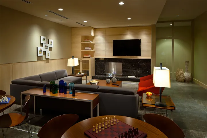 Lounge area featuring integrated flat-screen media, a dark stone fireplace surround, and recessed ceiling lighting