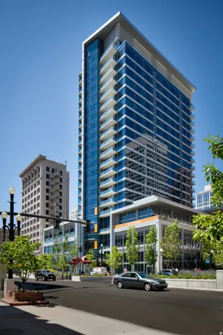 Modern high-rise residential building featuring extensive blue-tinted window elements and multiple private balconies