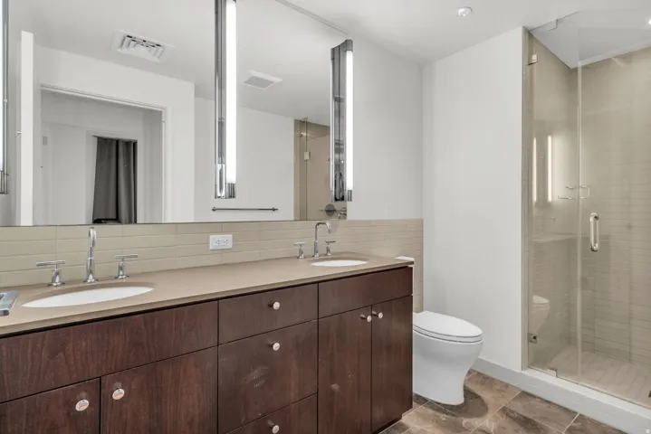 Bathroom featuring a dual-sink vanity with a dark wood-finish cabinet and light-toned countertop