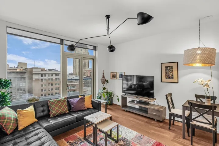Bright living area featuring expansive window wall, wood-finish flooring, high ceilings, a contemporary ceiling light fixture, and a modern pendant light