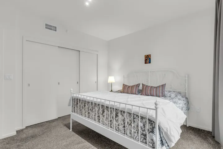 Spacious room featuring neutral carpeting, white walls, and a large sliding door closet