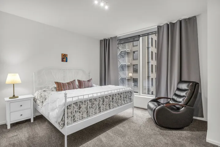 Bright bedroom with neutral wall paint and grey carpet flooring