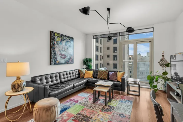 Living area featuring wood-finish flooring, a full-height window, and a glass-paneled door
