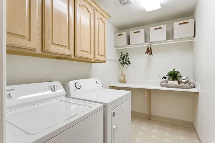 Laundry area featuring a built-in countertop, upper cabinetry, shelving, and patterned flooring