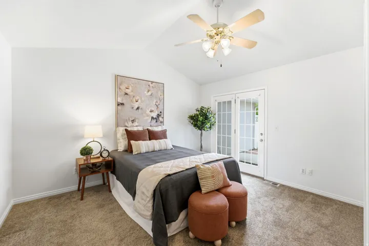 Vaulted ceiling with a ceiling fan, light-colored carpeting, white walls, and French doors providing direct outdoor access