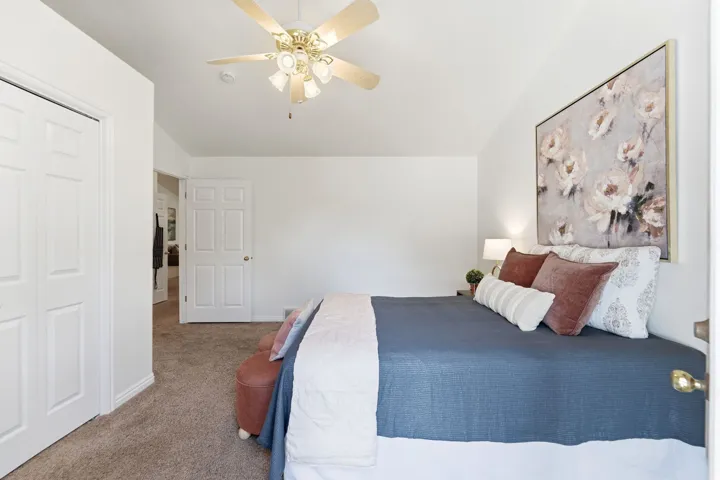 Carpeted room featuring a ceiling fan with integrated lighting, white six-panel doors, and a neutral wall color