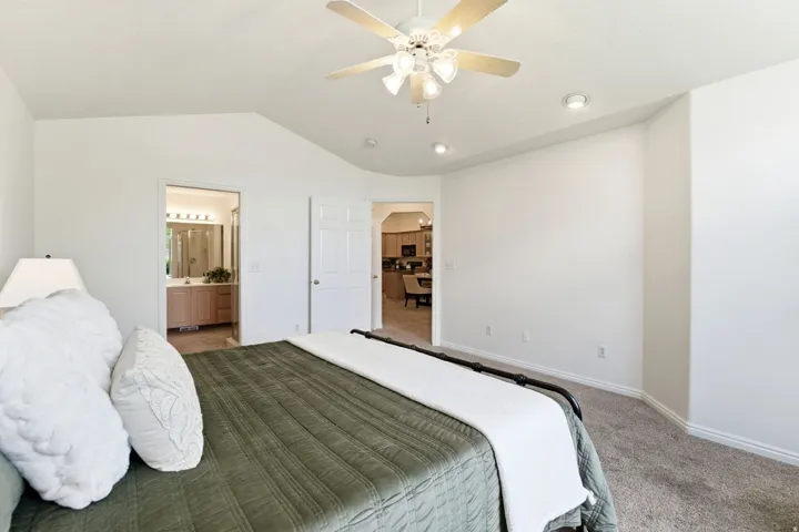 Vaulted ceiling bedroom with ceiling fan, recessed lighting, carpet flooring, and white baseboards