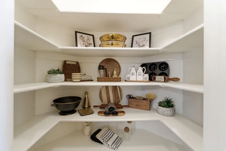 Walk-in pantry featuring wraparound shelving, white painted finishes, and a skylight