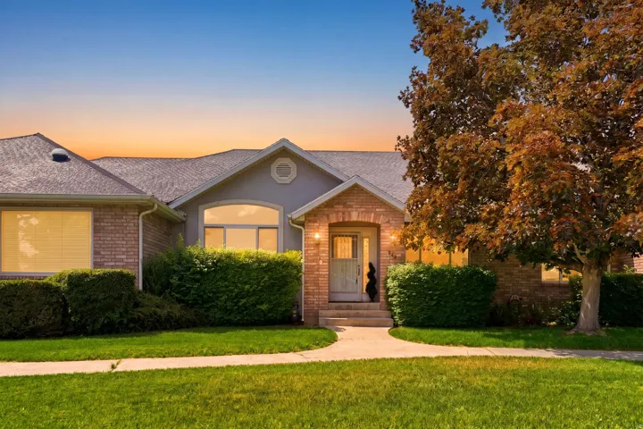 Brick and stucco exterior featuring a gabled roofline and an arched entry with a glass-paneled door