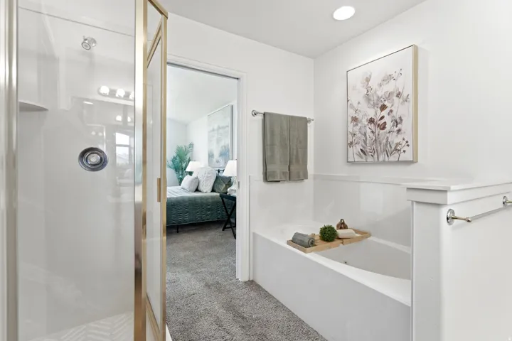 Bathroom featuring a built-in soaking tub and an enclosed shower with a glass and gold-toned frame
